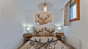 A bedroom with a bed featuring a deer print bedspread, two bedside lamps, and a ceiling light fixture. - 40m from ski slopes, floor -3, view ski slopes, fitness, swimming pool, sauna, balcony, tv (Les Orres)
