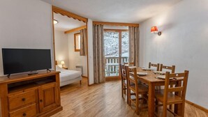A cozy room with a TV, wooden furniture, a bed, and a balcony with curtains. - 40m from ski slopes, floor -3, view ski slopes, fitness, swimming pool, sauna, balcony, tv (Les Orres)