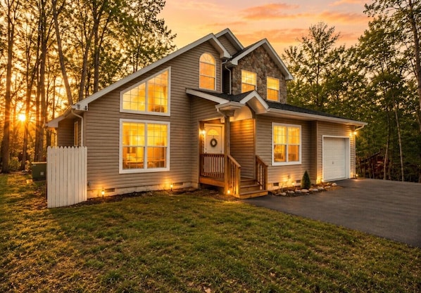 A two-story house with a front porch, a garage, and a well-maintained lawn.