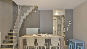 A modern kitchen with a wooden table, white chairs, and a staircase with a netted railing. - Duplex in Blankenberge Steps From Seafront (Blankenberge)