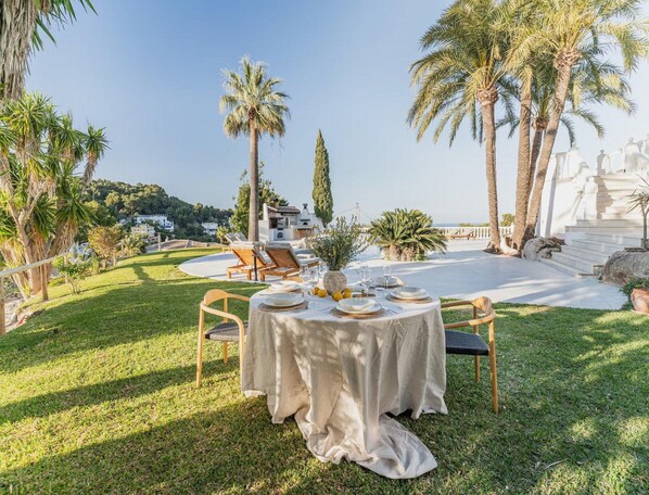 An outdoor dining area with a round table set for four, surrounded by chairs.