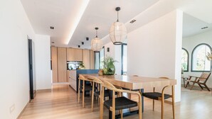 A modern kitchen with wooden cabinets, a central island, and pendant lighting. - Superb Villa With Private Lagoon Pool (Javea)