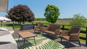 A deck with wicker furniture, a table, and a patterned rug.