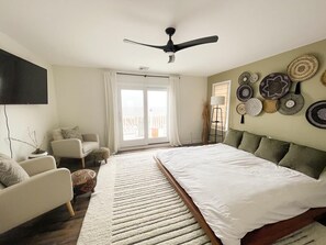 A bedroom with a bed, a chair, a ceiling fan, and wall decor. - Bayview Sands - Modern, Pet Friendly, 6 BR/3BA on the Water! (Lower Township)