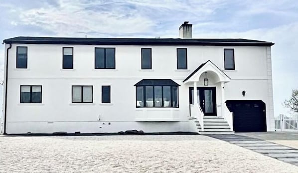 A white two-story building with a symmetrical facade, a central entrance with steps, and a small porch area. - Bayview Sands - Modern, Pet Friendly, 6 BR/3BA on the Water! (Lower Township)