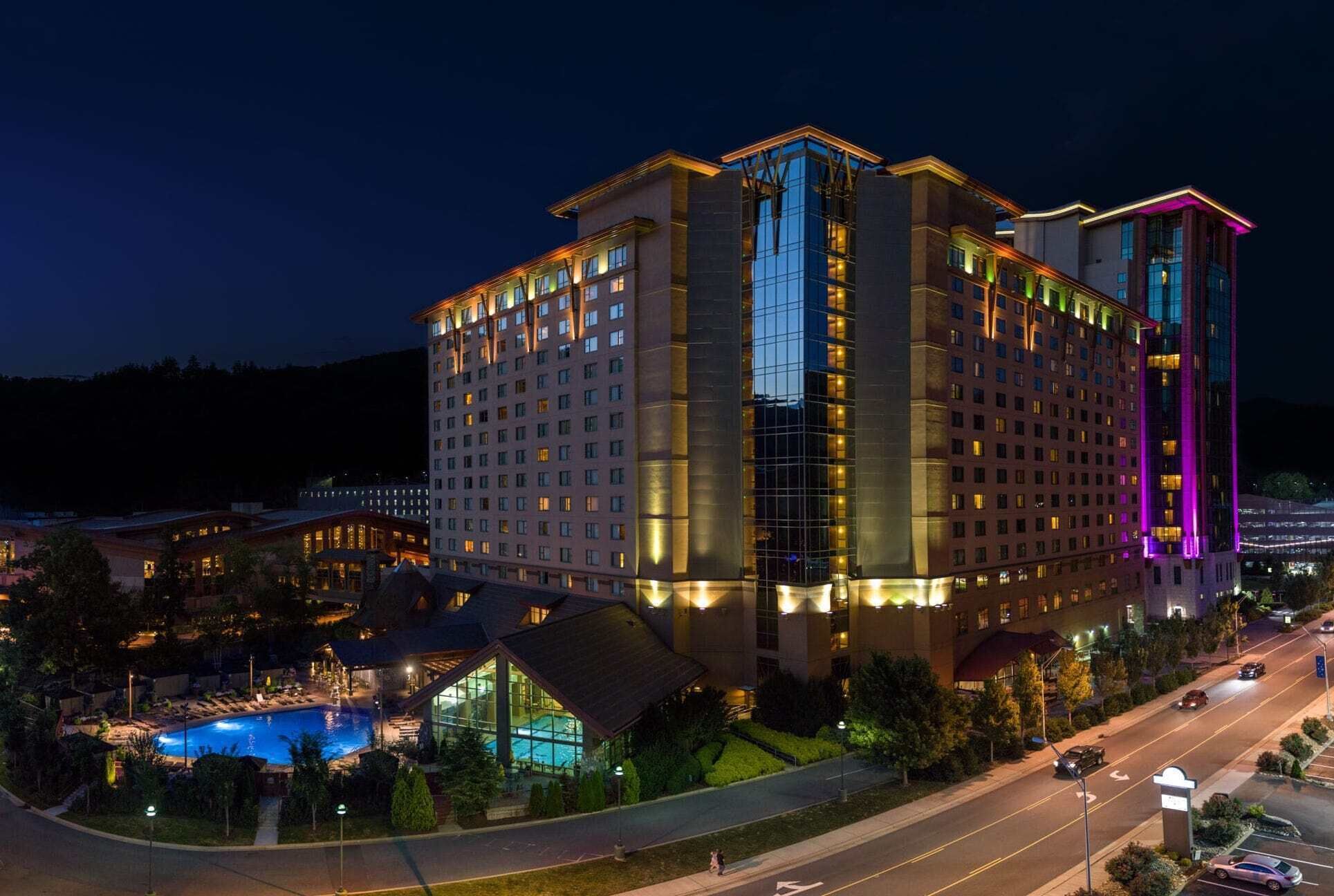 A multi-story hotel with a swimming pool and a parking area.
