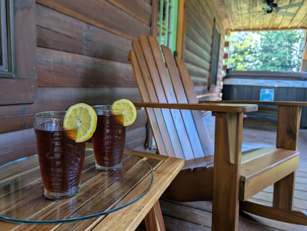 Two glasses of iced tea on a glass table with a wooden chair beside it.