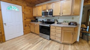 Una cocina con armarios de madera, horno de acero inoxidable, microondas y lavamanos.