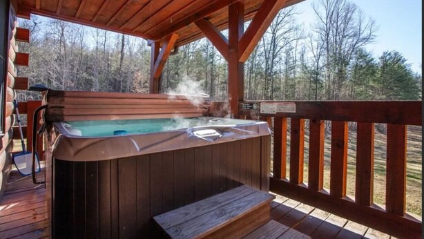 Un jacuzzi en una terraza de madera con vistas a árboles.