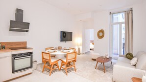A modern, well-lit living space with a kitchen, dining area, and a cozy seating area with a sofa and a coffee table.