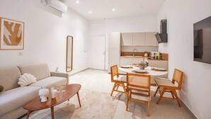 A modern living room with a sofa, coffee table, and dining area with chairs and a table set for two.