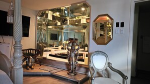 Una habitación con un espejo grande, una estatua y una silla.