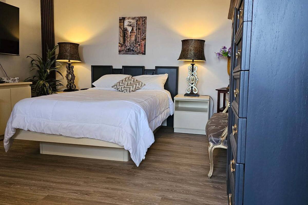 Une chambre à coucher avec un lit, des tables de chevet, une télévision et une armoire.