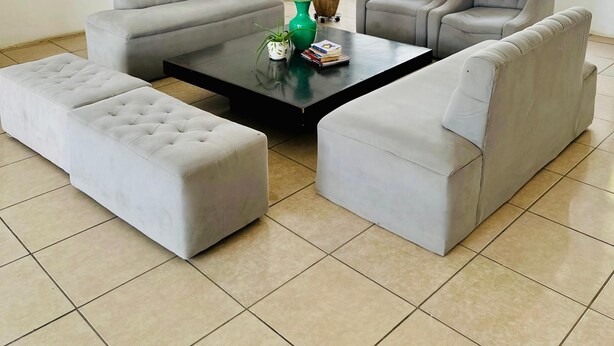 A modern living room with a sectional sofa, a coffee table, and a large window providing a view of the outdoors. - Los Vados Hotel  (Managua)