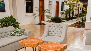 A modern living room with a grey sofa, two wooden side tables, and a grey armchair. - Los Vados Hotel  (Managua)