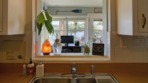 A kitchen with a large window, a hanging plant, a salt lamp, and a "No Smoking or Vaping" sign.