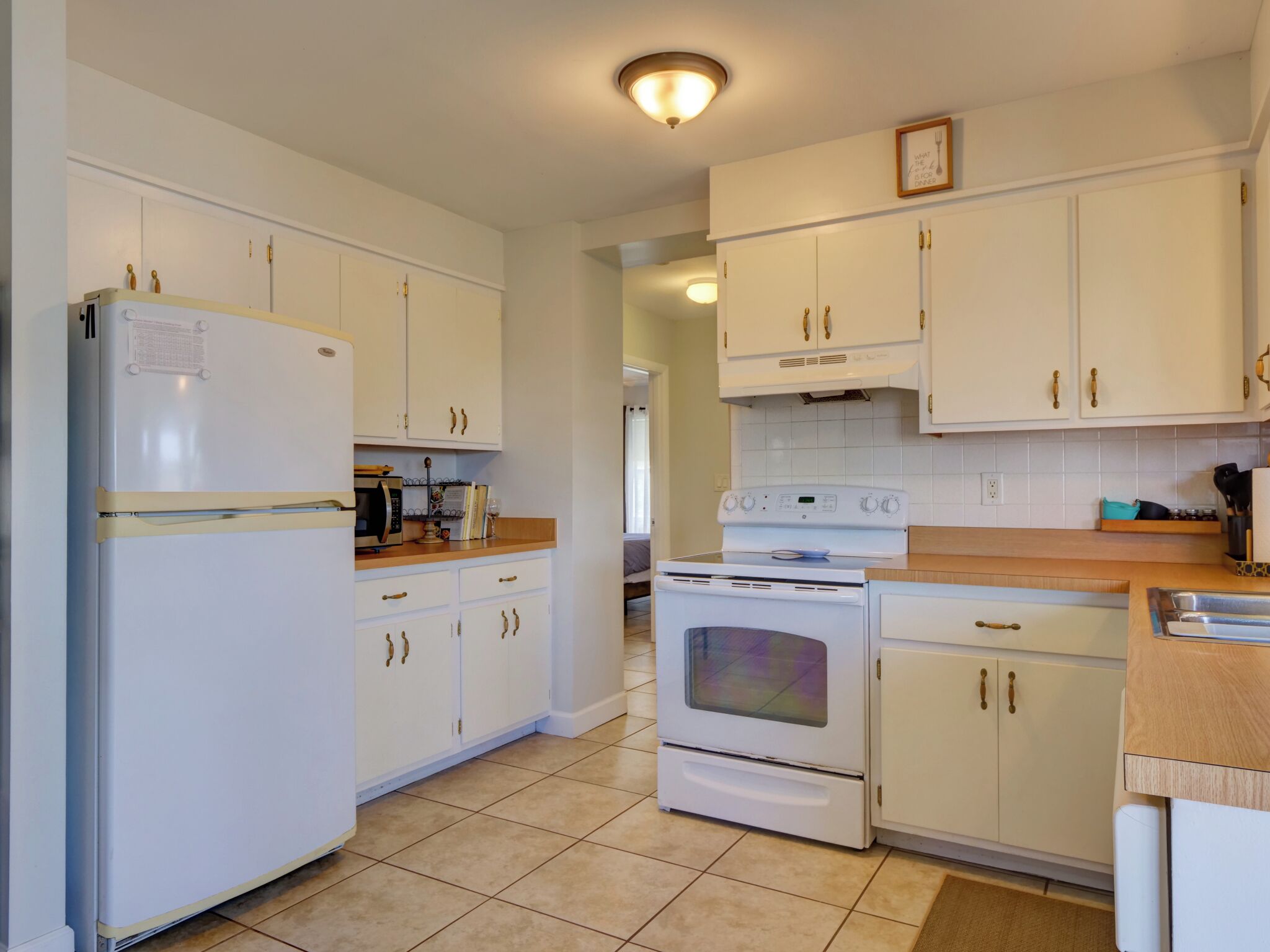A kitchen with white cabinets, a refrigerator, an oven, and a microwave.