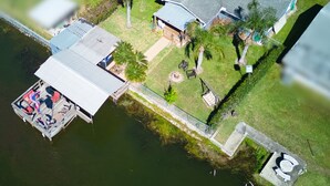 An aerial view of a house with a dock, a lawn, and a small garden area.