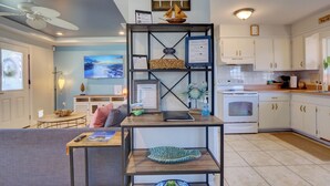 A modern kitchen with white cabinets, a built-in oven, and a dining area with a gray sofa and a wooden table.