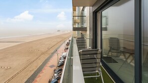 Ein Balkon mit Blick auf einen Strand und geparkte Autos.