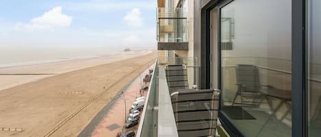 A balcony with a view of a beach and parked cars.