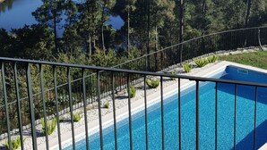 Une piscine avec vue sur un lac et des collines boisées.