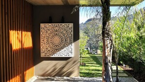 Un intérieur moderne agrémenté d’un décor mural à motifs, d’un mur à lattes de bois et offrant une vue sur un jardin luxuriant.