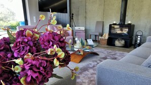 Un salon moderne avec une grande plante en pot, un canapé, une table basse et une cheminée.