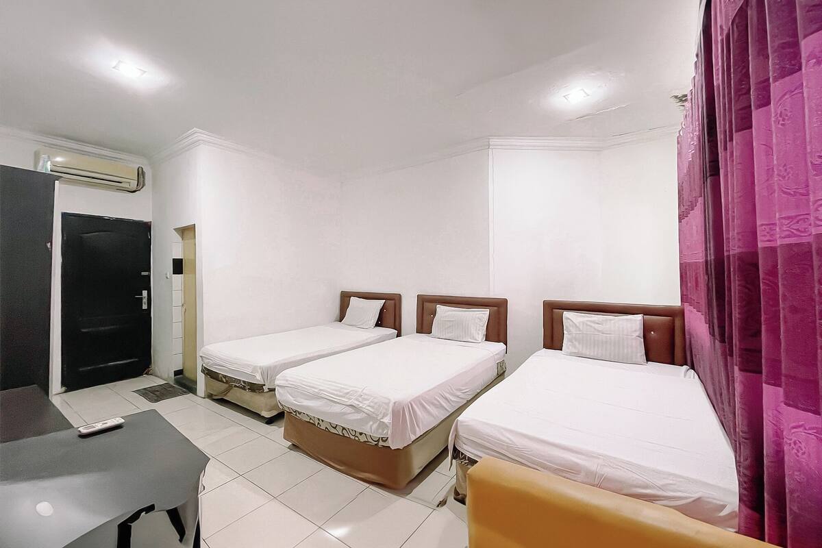 Habitación de hotel con dos camas individuales, un escritorio y una silla.