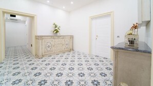 Una habitación con baldosas de suelo estampadas, un mueble color crema, una puerta blanca y un pequeño adorno sobre una encimera.