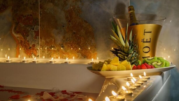 Una mesa con una botella de champán, frutas y velas.