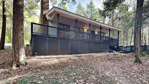 A cabin with a covered porch, surrounded by trees. - Koi at the Lake by Taylor Made Deep Creek (Oakland)