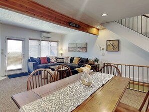 Una sala de estar con una mesa de comedor de madera, un sofá y una escalera.