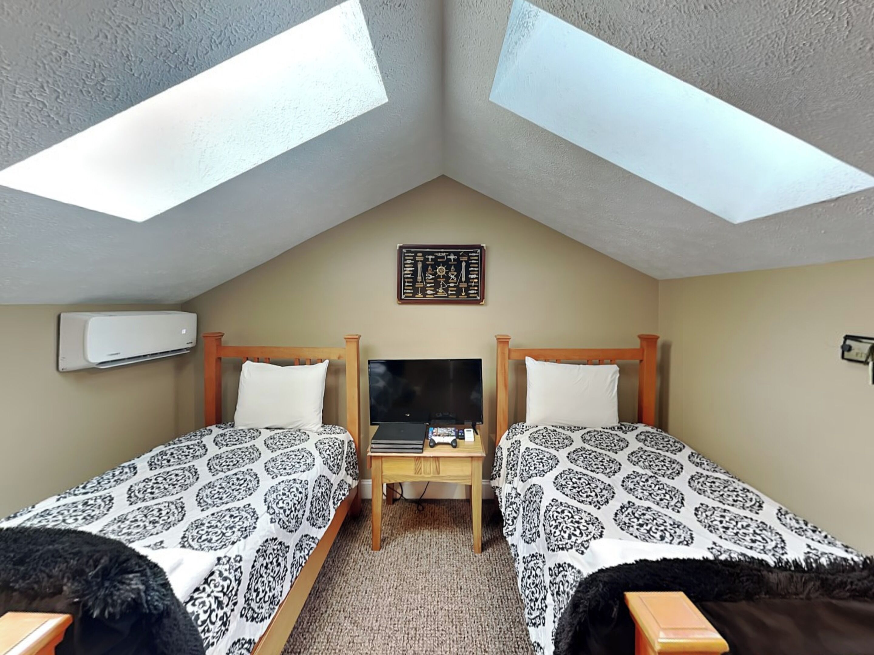 A bedroom with two beds, a TV, a small table, and an air conditioning unit.