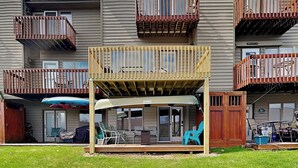 A multi-story residential building with balconies and a covered outdoor seating area with chairs and a table. - Happy Time by Taylor Made Deep Creek (McHenry)