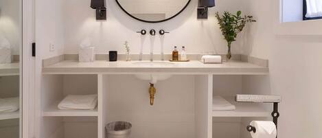 Een moderne badkamer met een ronde spiegel, een witte wastafel en een toilet.