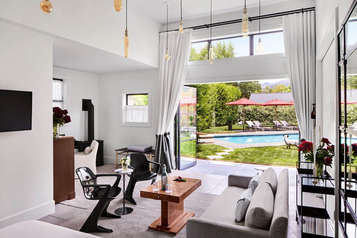 A modern living room with a large window, a pool, and outdoor seating.