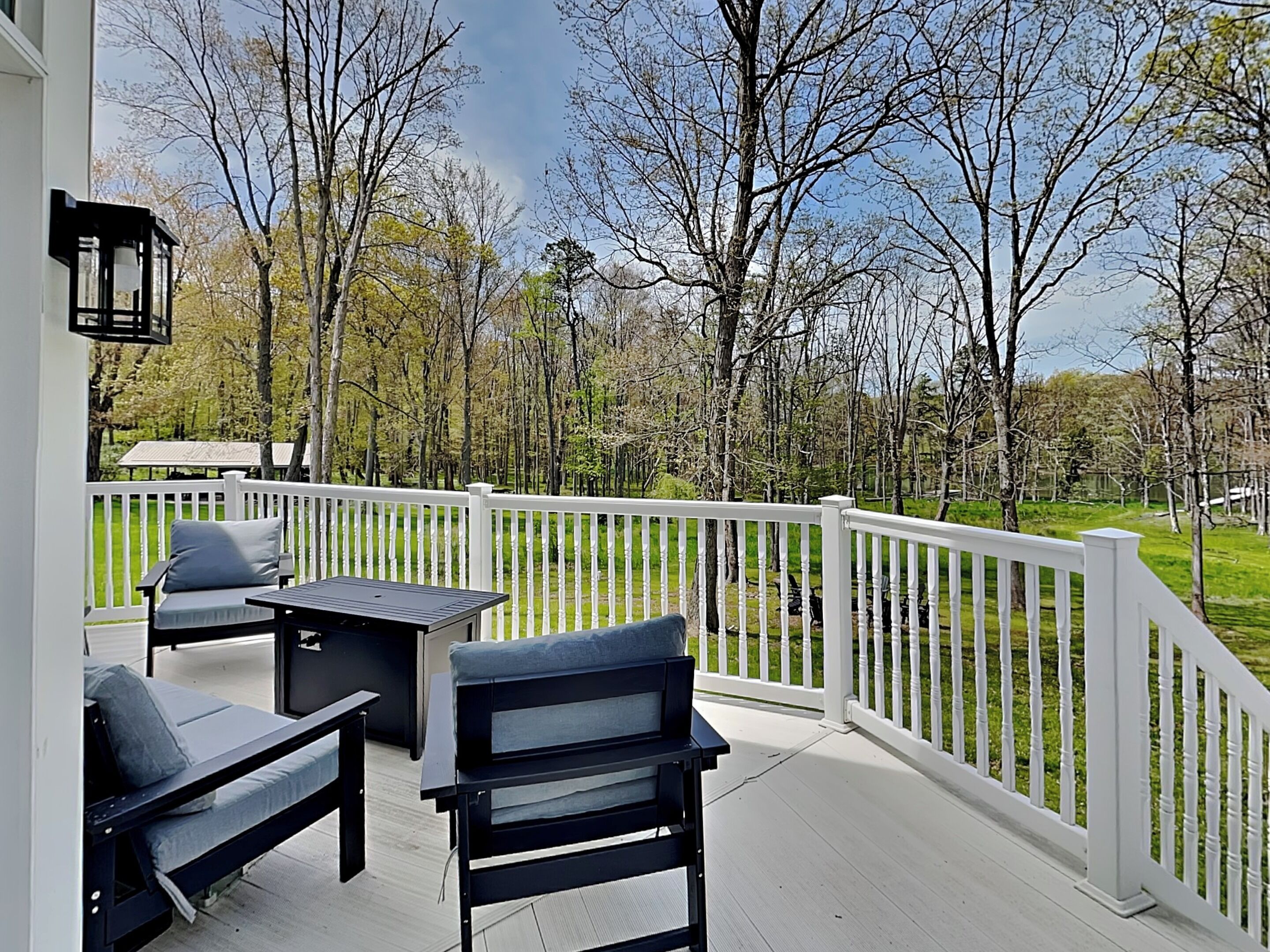 A covered outdoor area with a white railing, a table, and two chairs.
