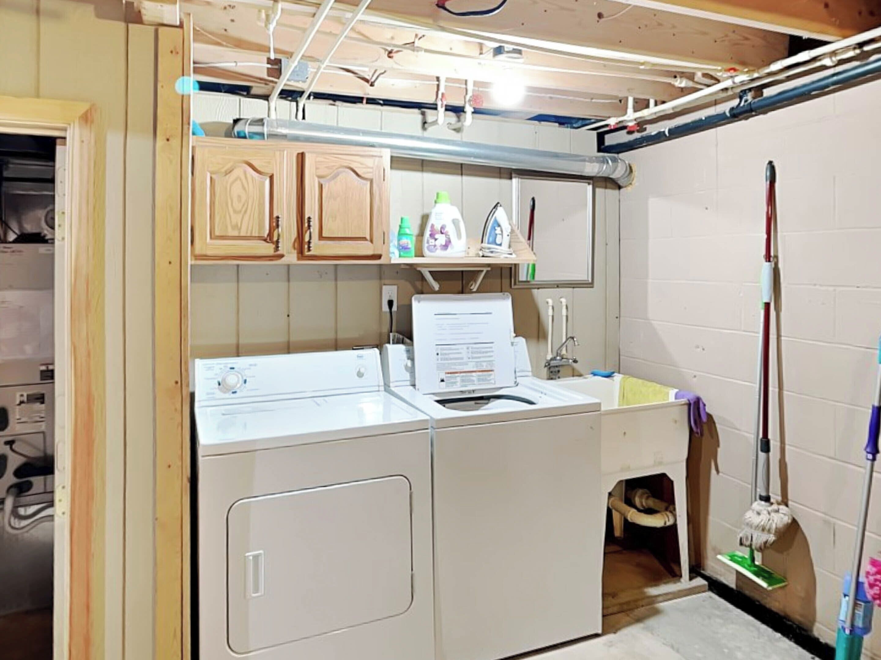 A laundry room with a washing machine, dryer, and ironing station.