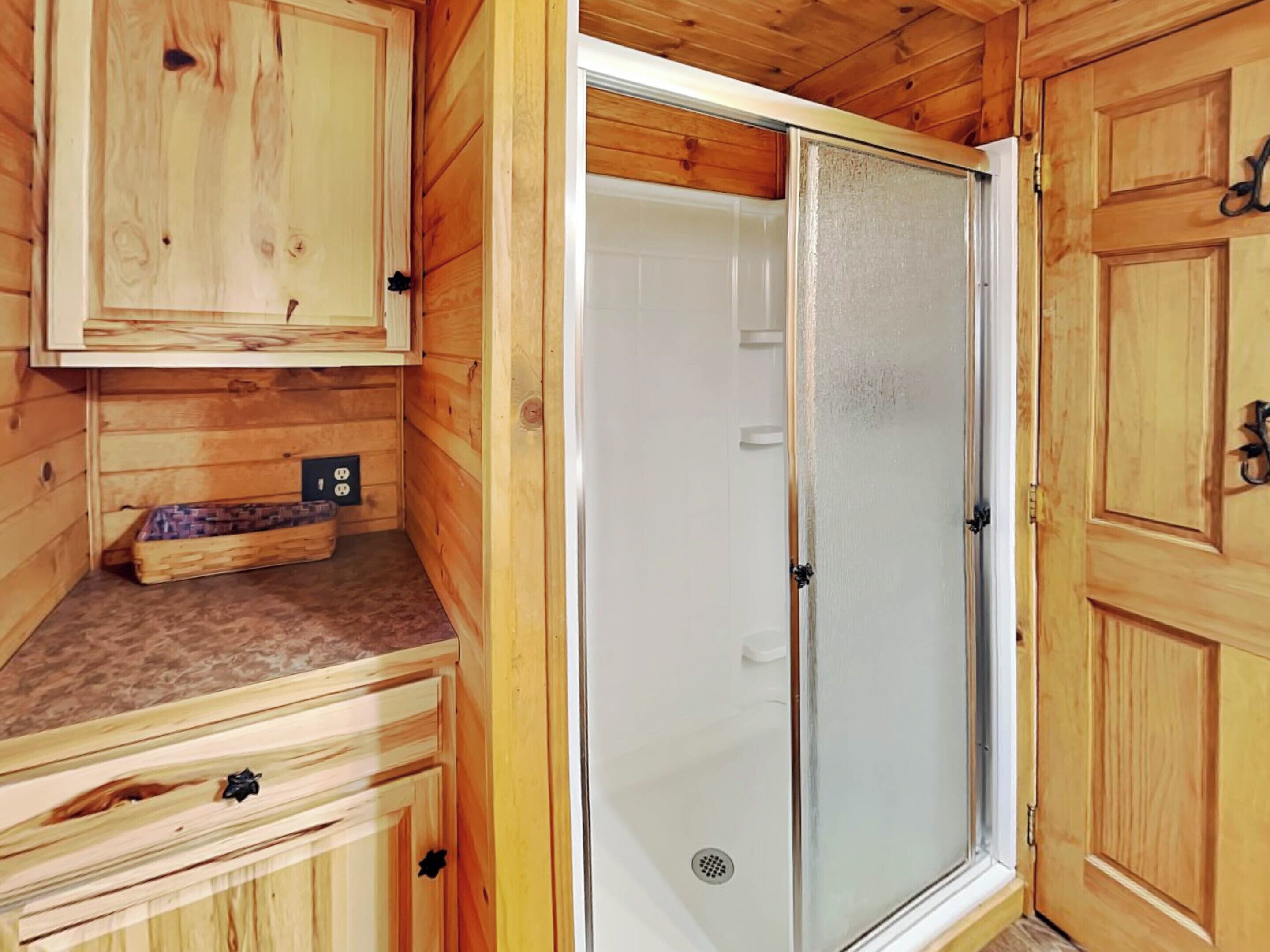 A wooden cabin interior with a shower, a small sink, and a cabinet.