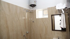 Un bagno con doccia, porta asciugamani e specchio.