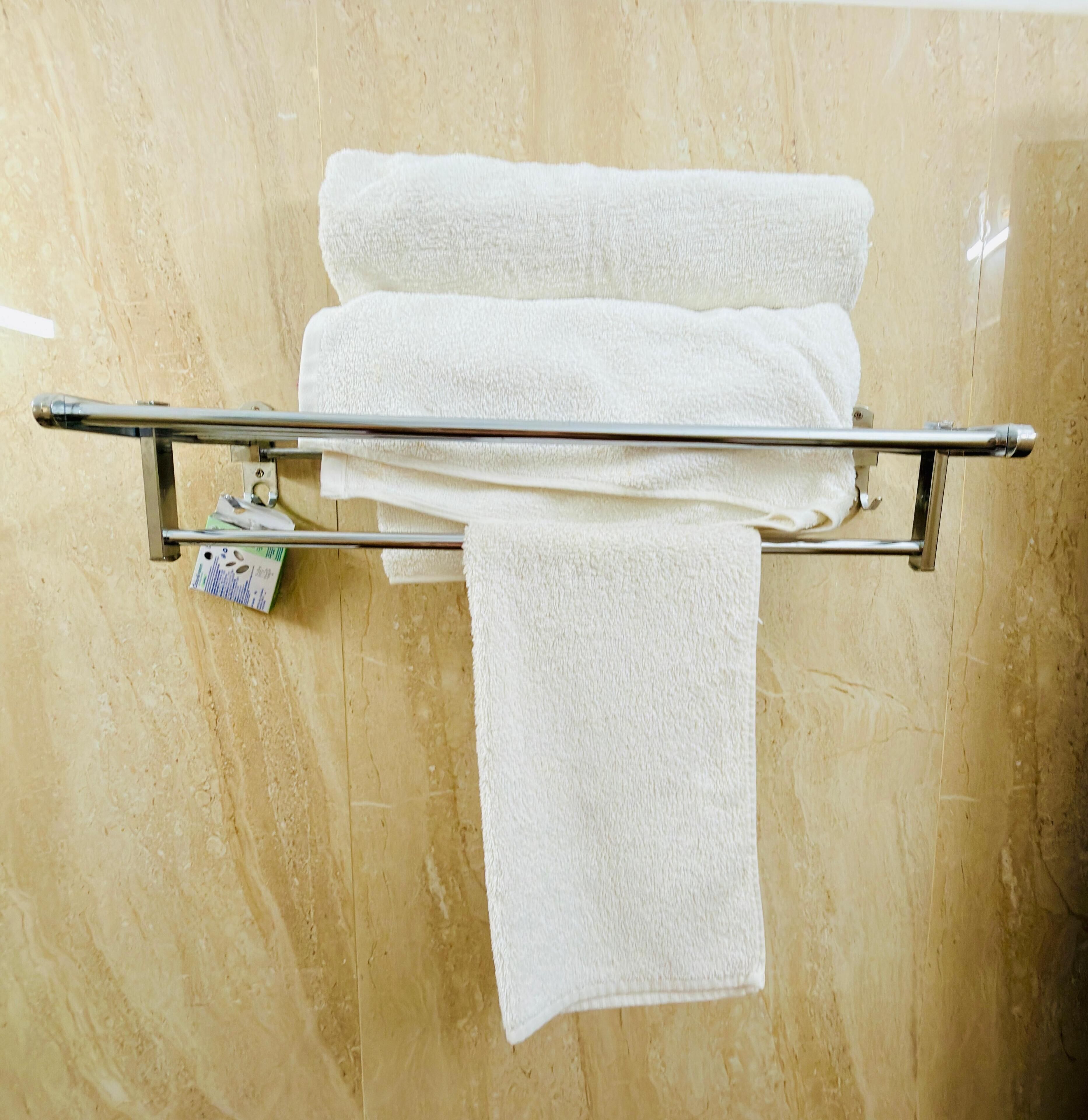 A bathroom with a towel rack holding three white towels.