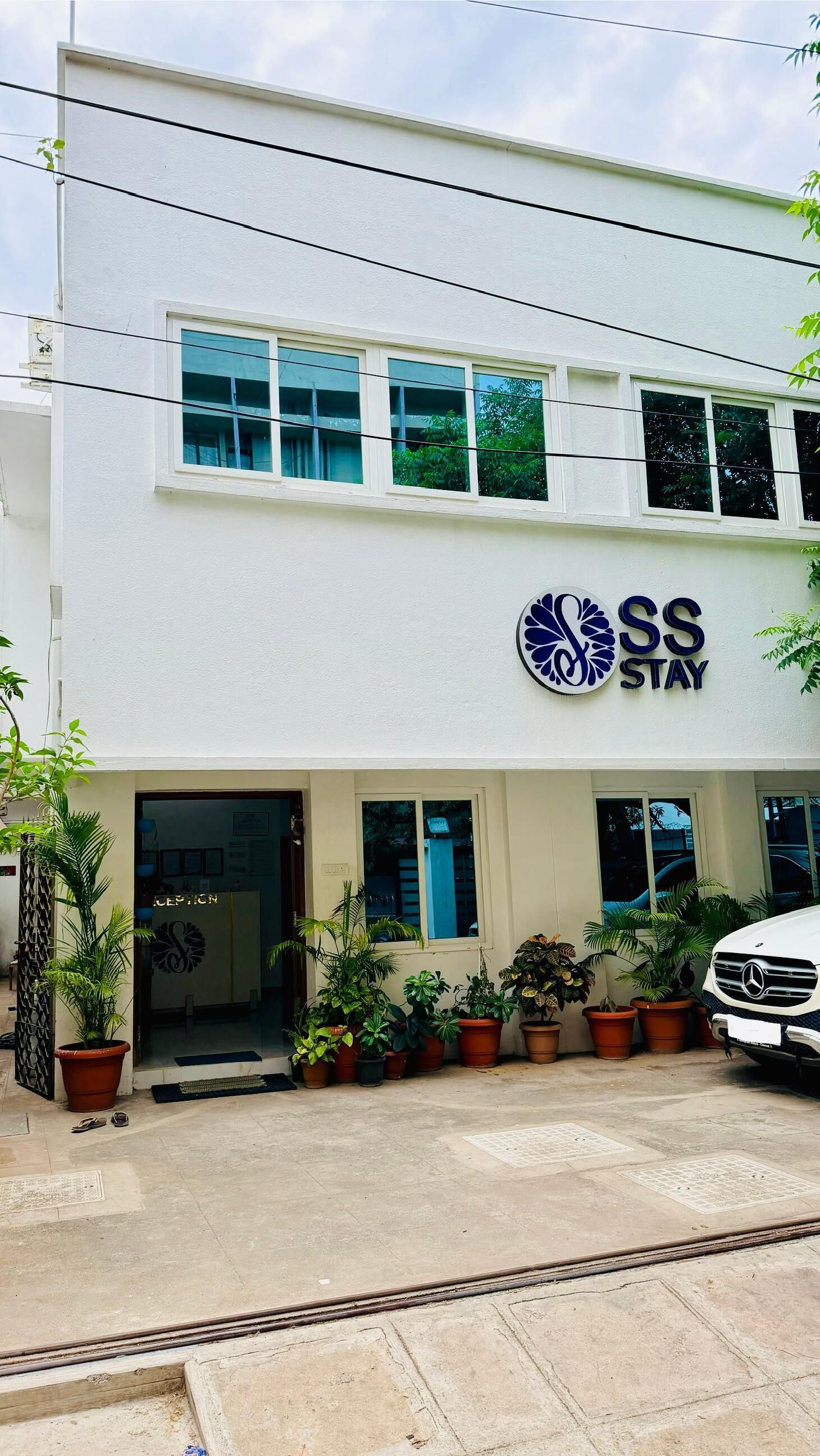 A building with a sign reading 'SS STAY' and a Mercedes-Benz parked in front.