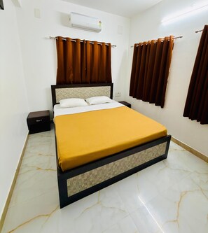 A hotel room with a bed, curtains, an air conditioning unit, and a nightstand. - SS STAY (Chennai)