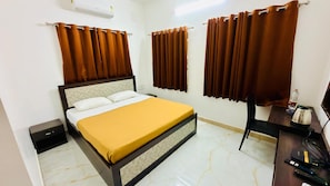 A hotel room with a bed, a desk, a chair, a water bottle, and a kettle. - SS STAY (Chennai)