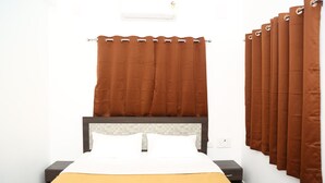 Una camera d'albergo con un letto, un comodino, un condizionatore d'aria a parete e una tenda.