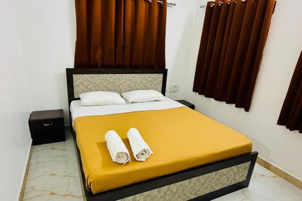 Un lit avec un matelas jaune, deux oreillers et deux serviettes enroulées.