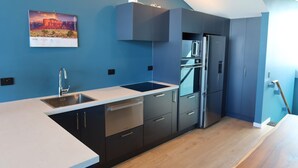 A modern kitchen with a built-in oven, stainless steel appliances, and a blue accent wall. - Princes Wharf - Penthouse - Stunning Views (Auckland)