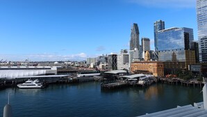 A waterfront cityscape with modern buildings, including a distinctive curved skyscraper and a glass building with the Deloitte logo. - Princes Wharf - Penthouse - Stunning Views (Auckland)