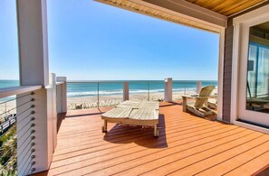 A wooden deck with a lounge chair and two Adirondack chairs overlooking a beach. - One Step Away Upper - 6 bedrooms (Carolina Beach)